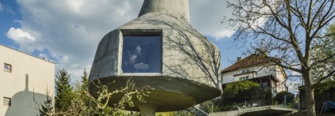 large gray home on a pillar with a large window