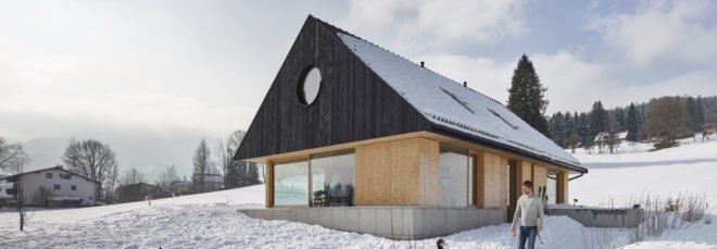 exterior of light timber home with dark gabled roof