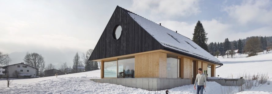 exterior of light timber home with dark gabled roof