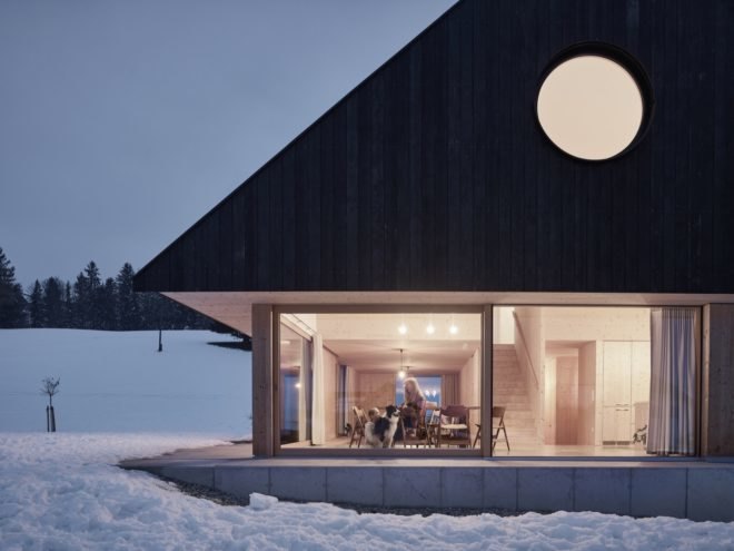 home exterior with large sliding glass doors and a round window ion the gabled roof portion
