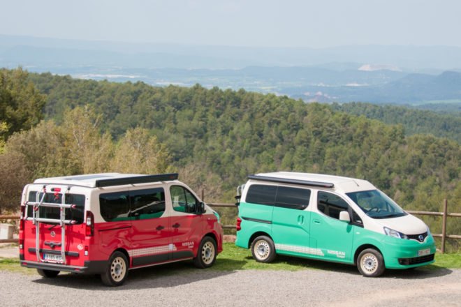 a red camper parked next to a light green camper