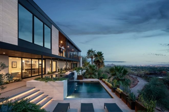 view of modern home with pool at dusk
