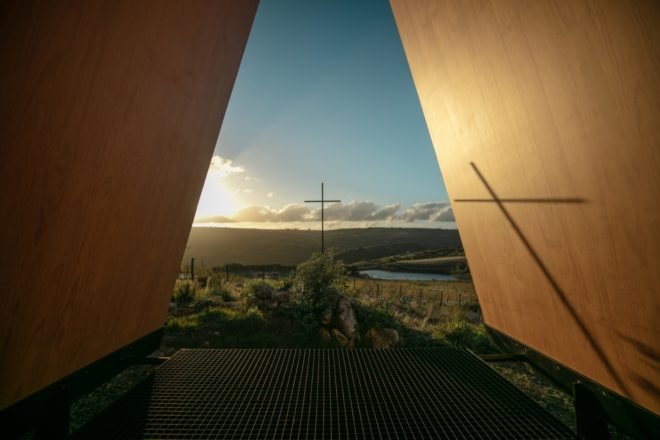 cross on landscape with its shadow on the interior of the chapel