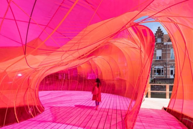 Person walking through bright pink interior of the pavilion