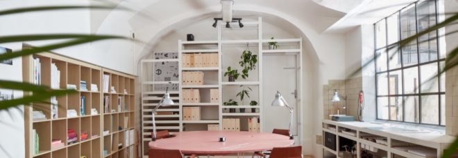 office space with light pink tables and chairs and large cubby bookshelves