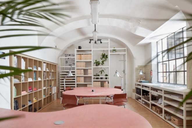 office space with light pink tables and chairs and large cubby bookshelves