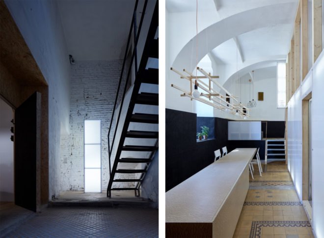 On the left, a staircase. On the right, a long narrow table and chairs and potted plants in a window