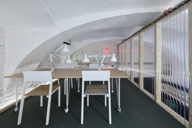upstairs work space with light desks and chairs and white desk lamps under a curved ceiling