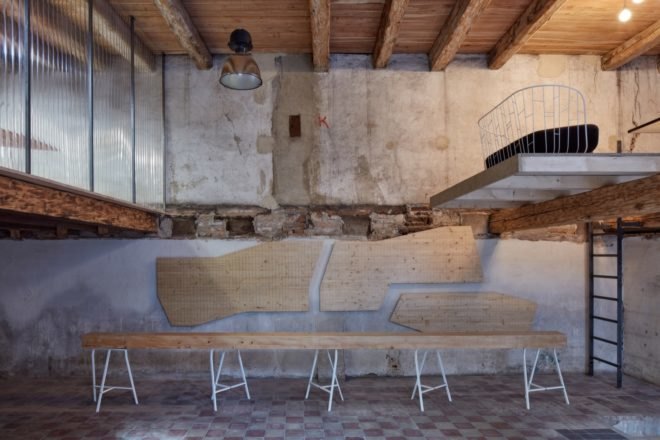 post-industrial room with long timber bench and lofts on the right and left