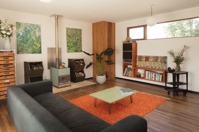 living room with gray couch, orange carpet, wood burning stove and green coffee table
