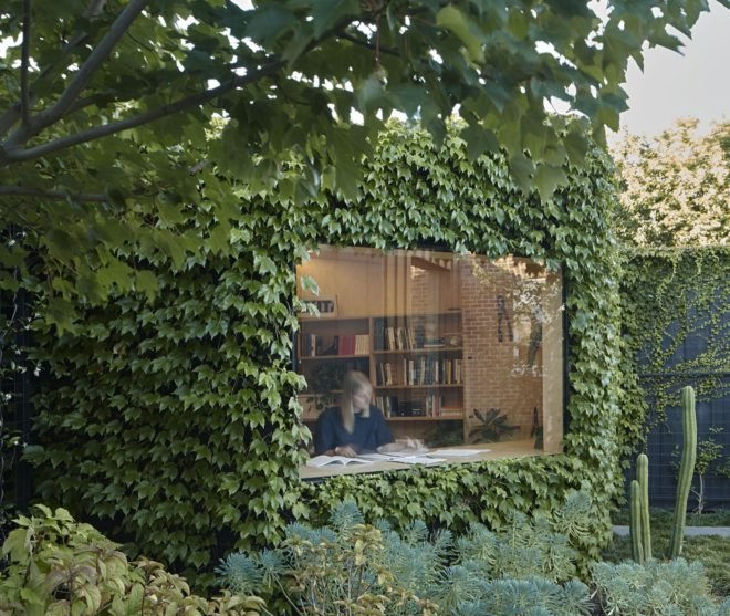 ivy-covered exterior of structure with person reading and writing inside