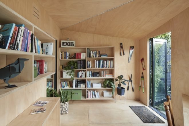 interior workspace with large bookshelf, hanging garden tools and potted plants