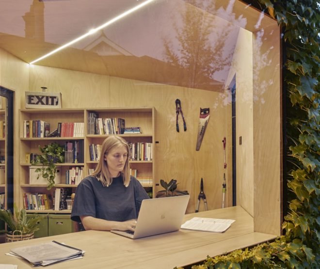 View from outside looking into large window at person typing on computer