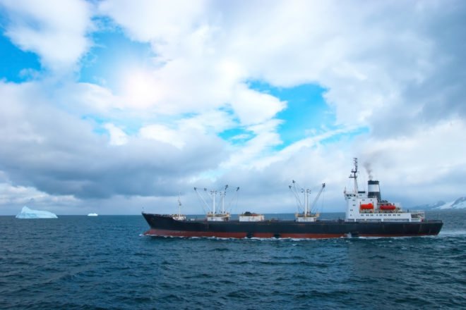 Fishing trawler in ocean near icebergs