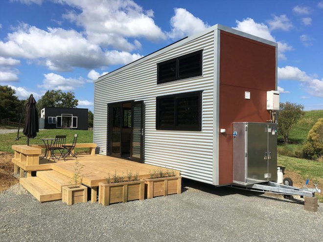 white tiny home with light wood deck in front