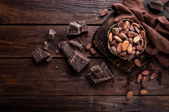 Dark chocolate and cocoa beans on dark wood background