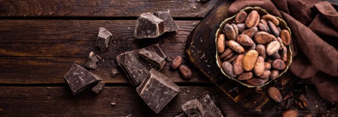 Dark chocolate and cocoa beans on dark wood background