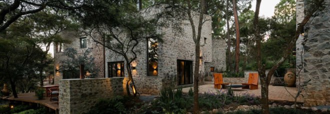 Stone home with outdoor patio surrounded by forest