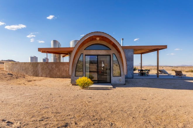 back of home with curved roof over rear entrance and a side outdoor patio