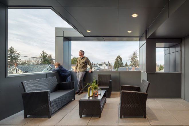 man on exterior deck with furniture and city views