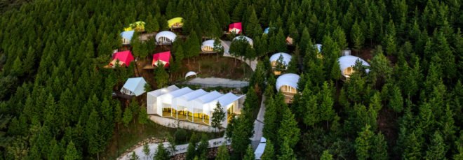 white building surrounded by colorful smaller buildings in forest