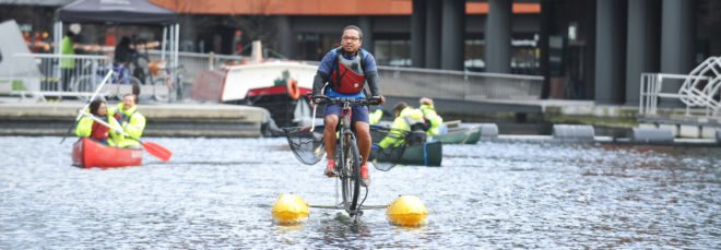 Man pedaling on a floating bike down the river