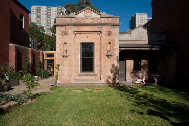 Pink brick exterior of remodeled home with green lawn