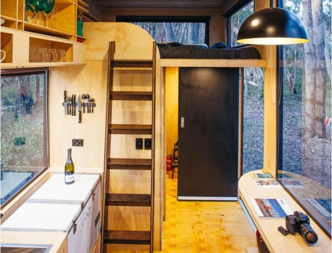 wood-lined interior with small kitchen area and wood ladder leading up to sleeping loft