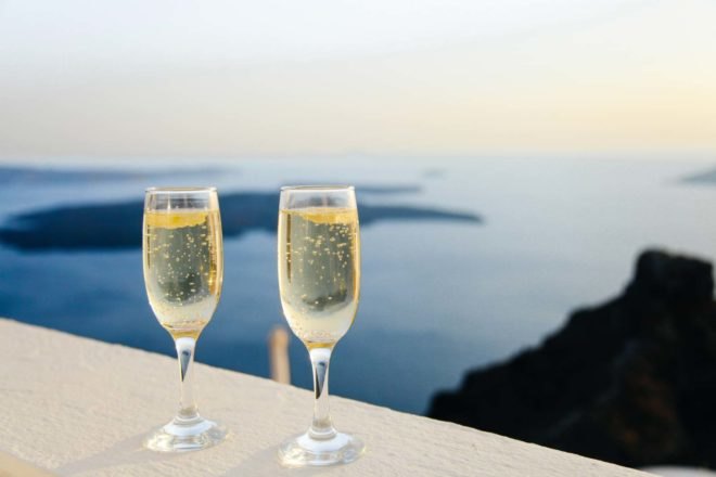 two champagne glasses on a balcony overlooking the sea
