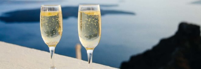 two champagne glasses on a balcony overlooking the sea