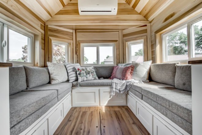 a u-shaped sofa with grey cushions and windows