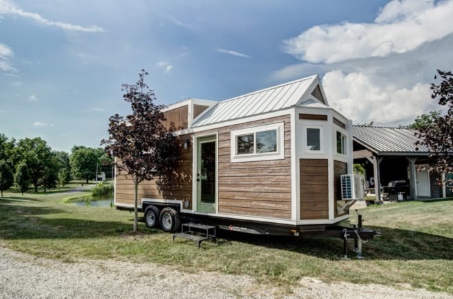 a tiny home on wheels with light wood siding and white trim