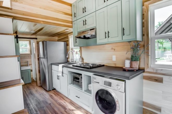 a kitchen with light green cabinets and a washing machine