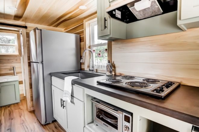 a kitchen with a four burner stove top, sink and refrigerator
