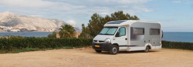 camper van on a beach with mountains in the background