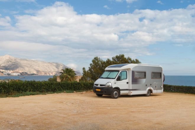 camper van on a beach with mountains in the background