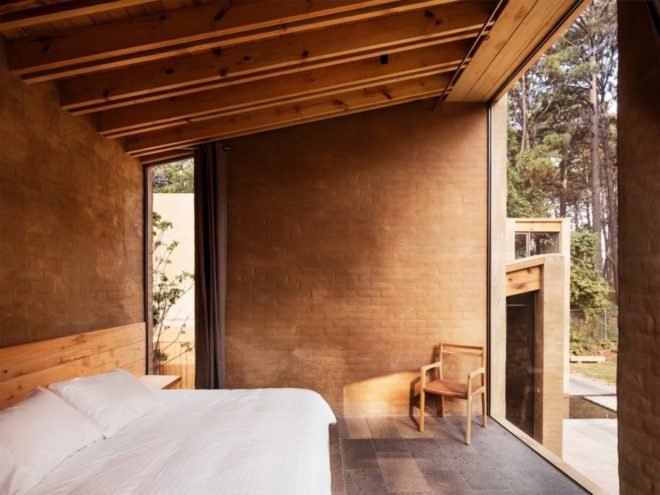 bedroom with full-height windows, wood ceiling beams, and light pink brick walls