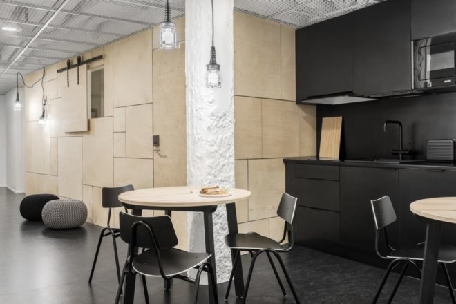 communal space with kitchen with black cabinetry and light wood dining tables with black chairs