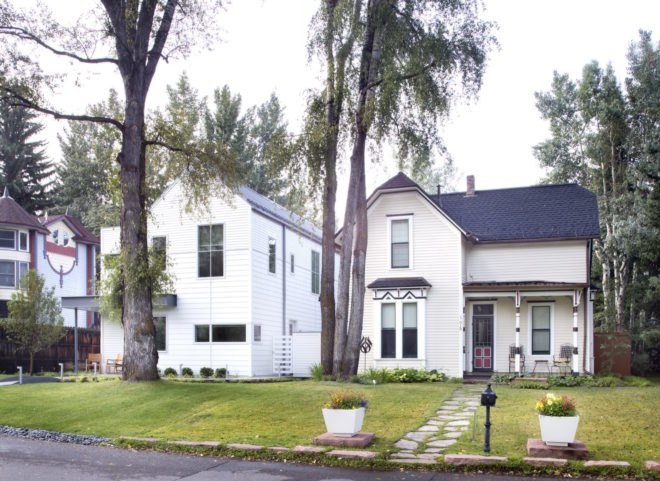 new gabled white home next to a white Victorian home