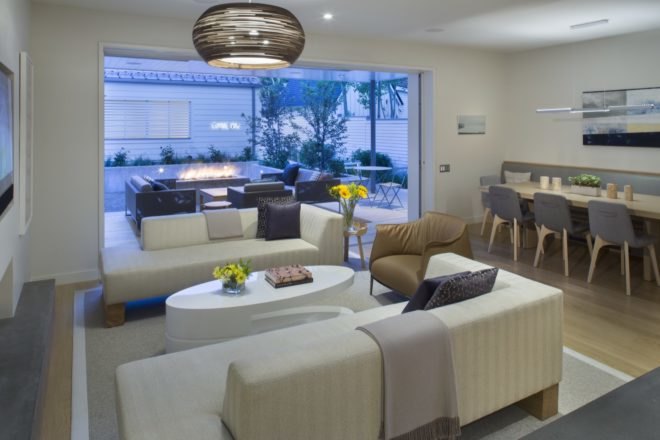 living room with white couches and leather chair with large doorway opened up to outdoor patio