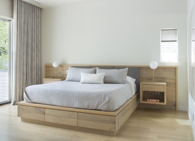 master bedroom with light gray bed tucked into a light wood bed frame and headboard