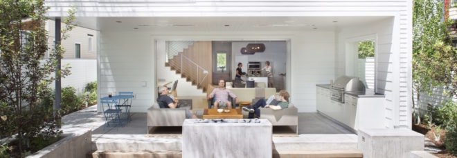 People lounging on outdoor deck space behind a white home