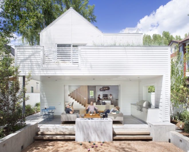 People lounging on outdoor deck space behind a white home