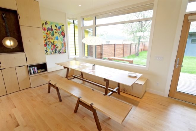 dining area with picnic-style light wood table near large window