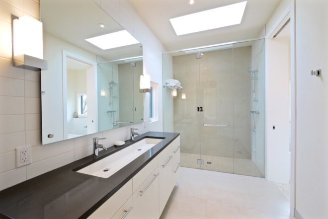 bathroom with white cabinets, long sink, large shower and large mirror