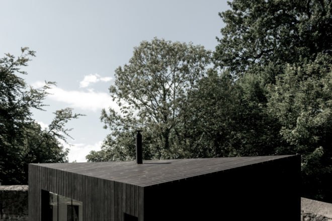 an angular roof with tree tops in the distance