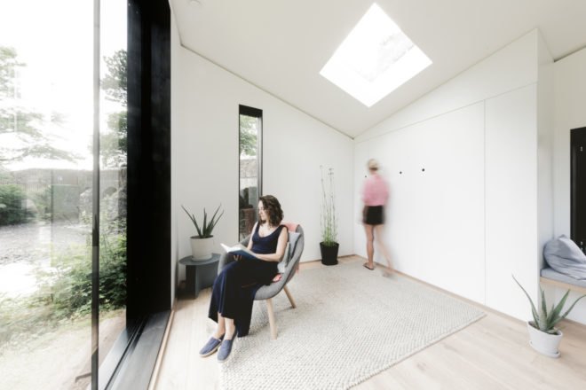 a lady dressed in black sitting in a chair in an all-white room