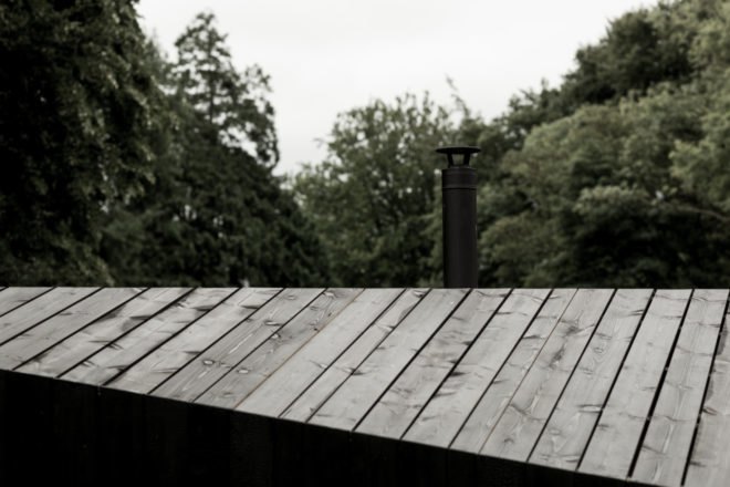 a slanted black roof with a slender black chimney