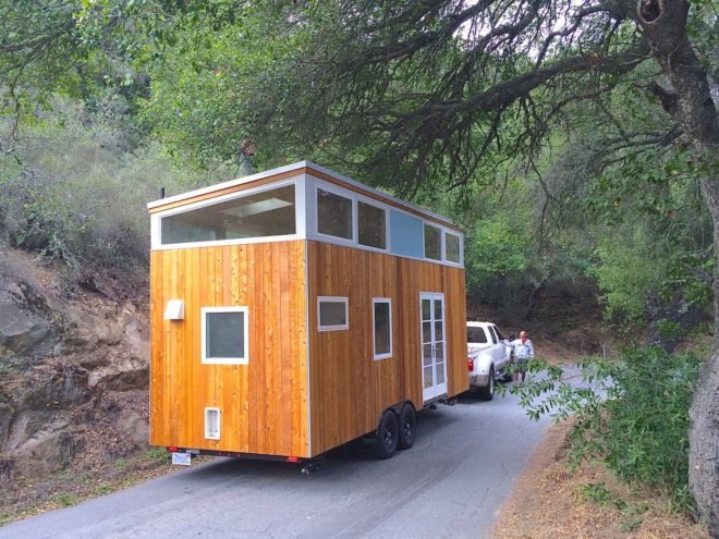 Tiny wooden home on wheels pulled by a truck