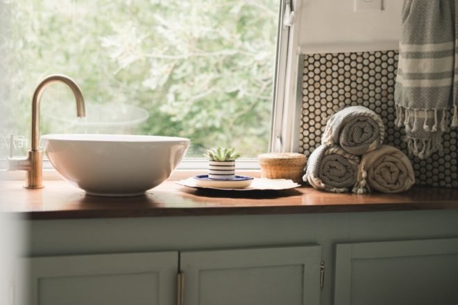 bathroom with green cabinetry, rolled towels, and white bowl sink
